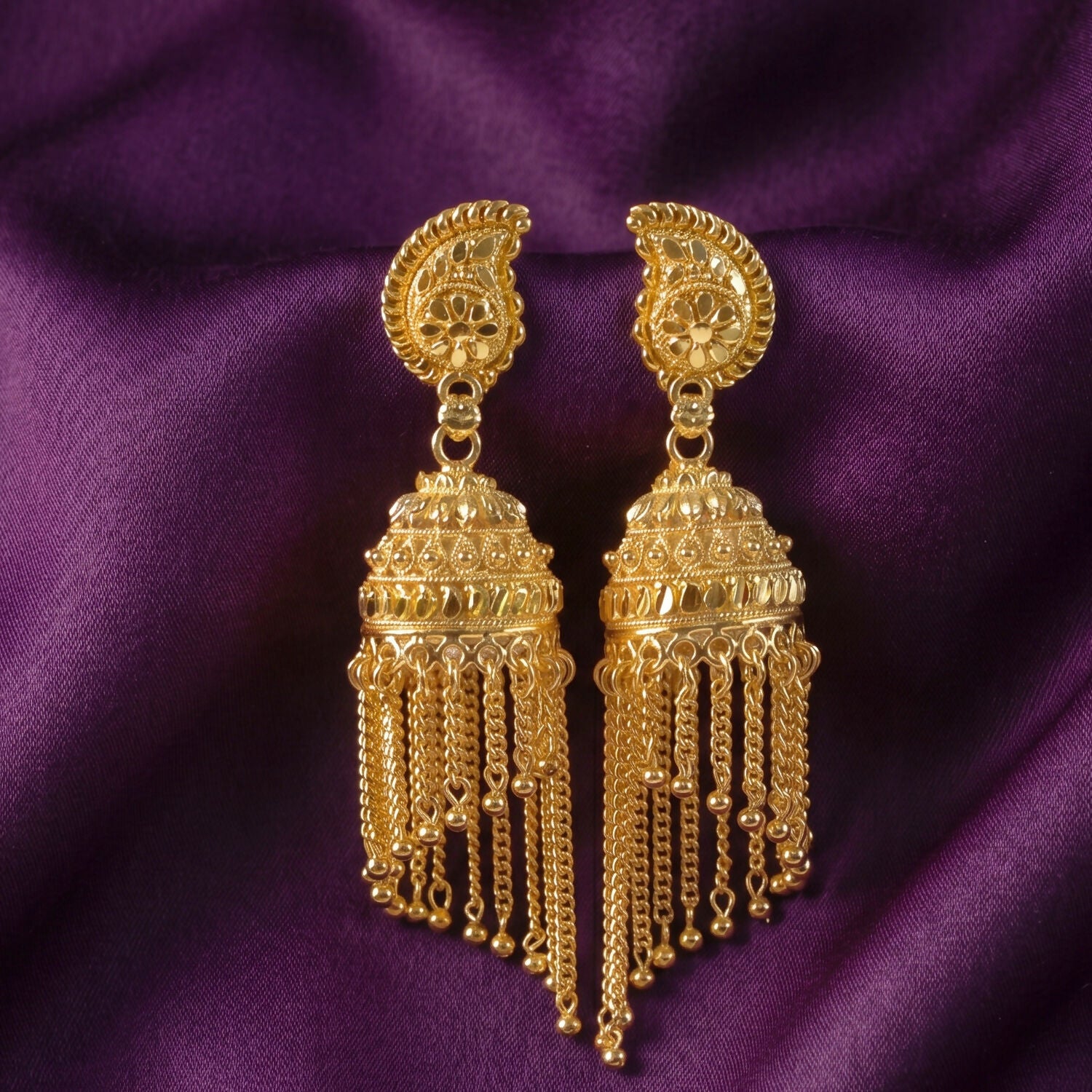 Close-up of gold-plated jhumka earrings with intricate chain detail