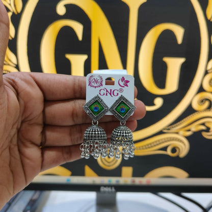 A pair of traditional oxidised jhumka earrings with a clear view of their ethnic design.