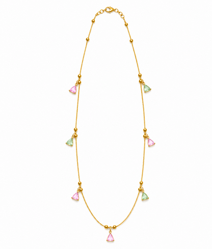 A gold-plated necklace with pink and mint green triangular charms is laid flat against a clean white background.