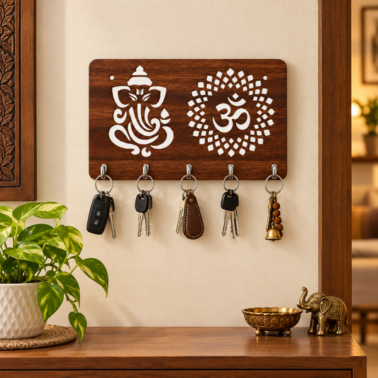 A wooden key holder with white Ganesh and Om symbols, holding five sets of keys, next to a plant and a brass elephant.