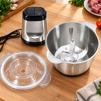 Disassembled stainless steel food chopper parts, including the motor, bowl with blade, and clear lid, on a wooden surface.