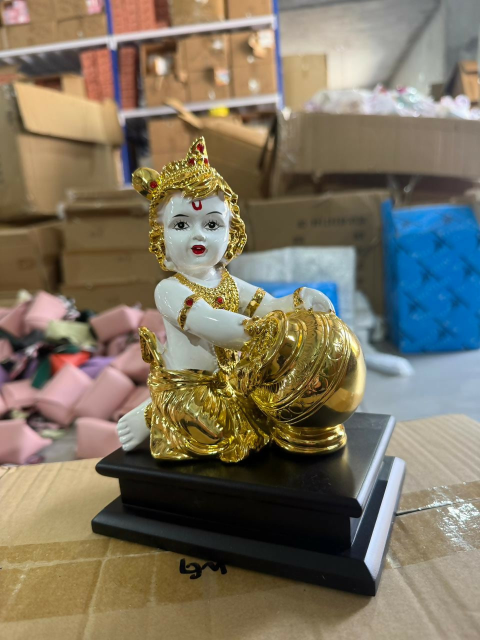 Close-up of golden Bal Krishna idol holding butter pot
