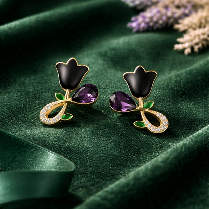 Black floral stud earrings worn with gold plating and green leaf accents