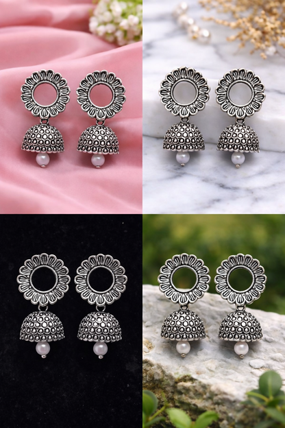 Pair of oxidized silver floral jhumka earrings placed on a white background