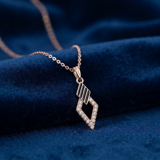 A rose gold necklace with a geometric pendant featuring black enamel stripes and clear crystals, resting on a dark blue