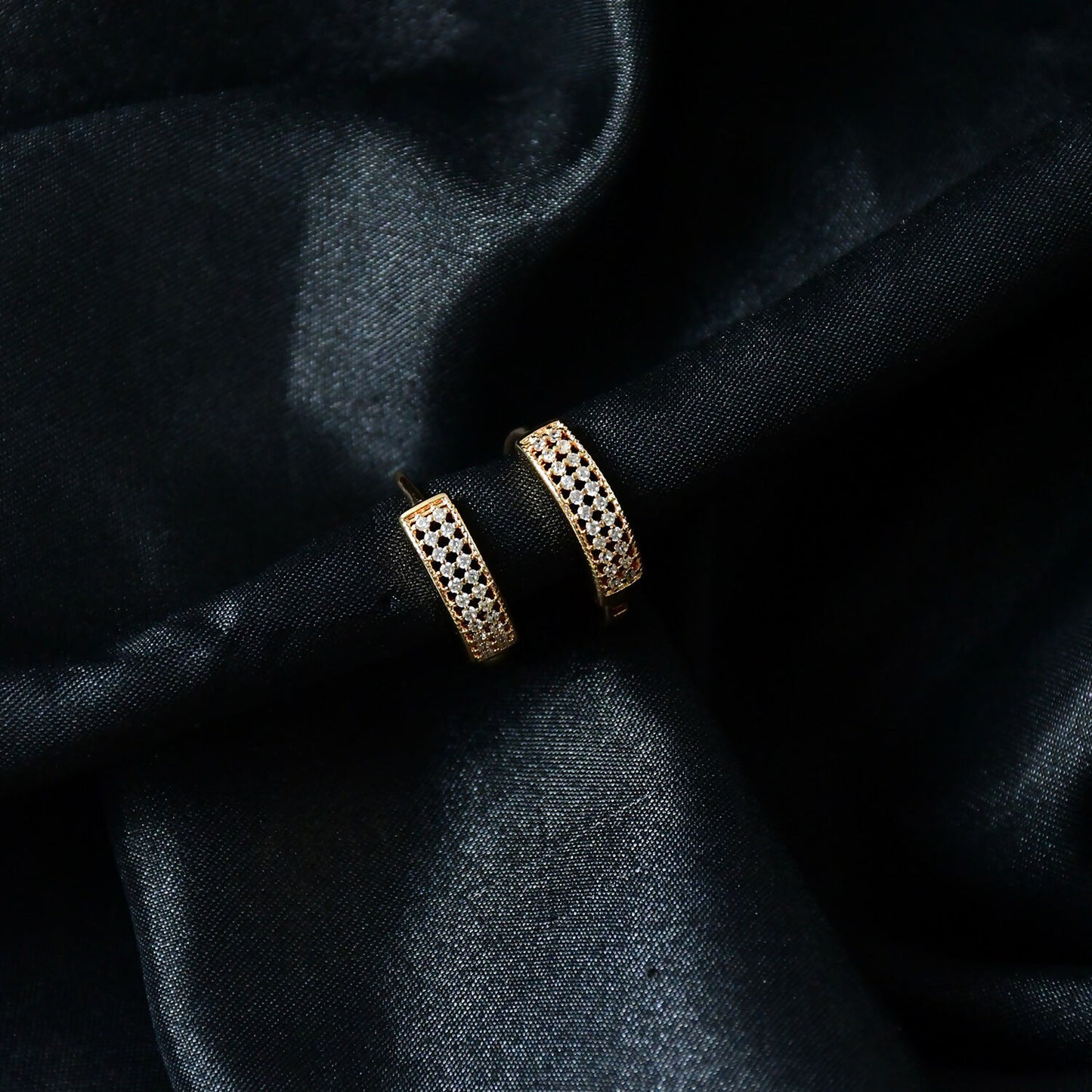 Pair of gold plated diamond hoop earrings displayed with sparkling details