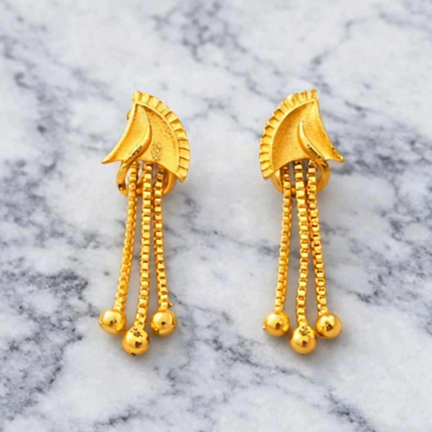 Close up of golden finish and shiny stones on drop earrings
