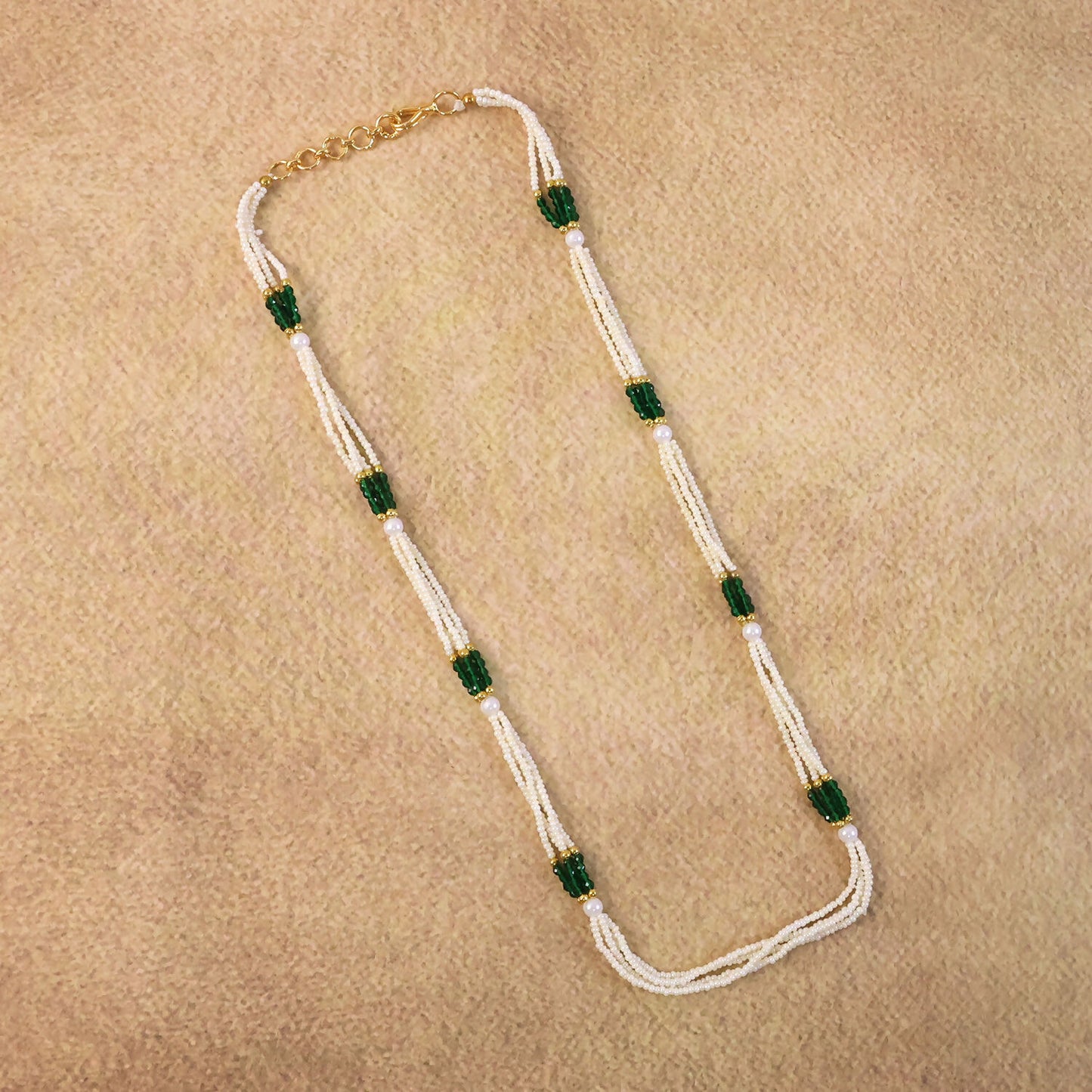 Close-up of green accent beads on pearl mala necklace with gold details
