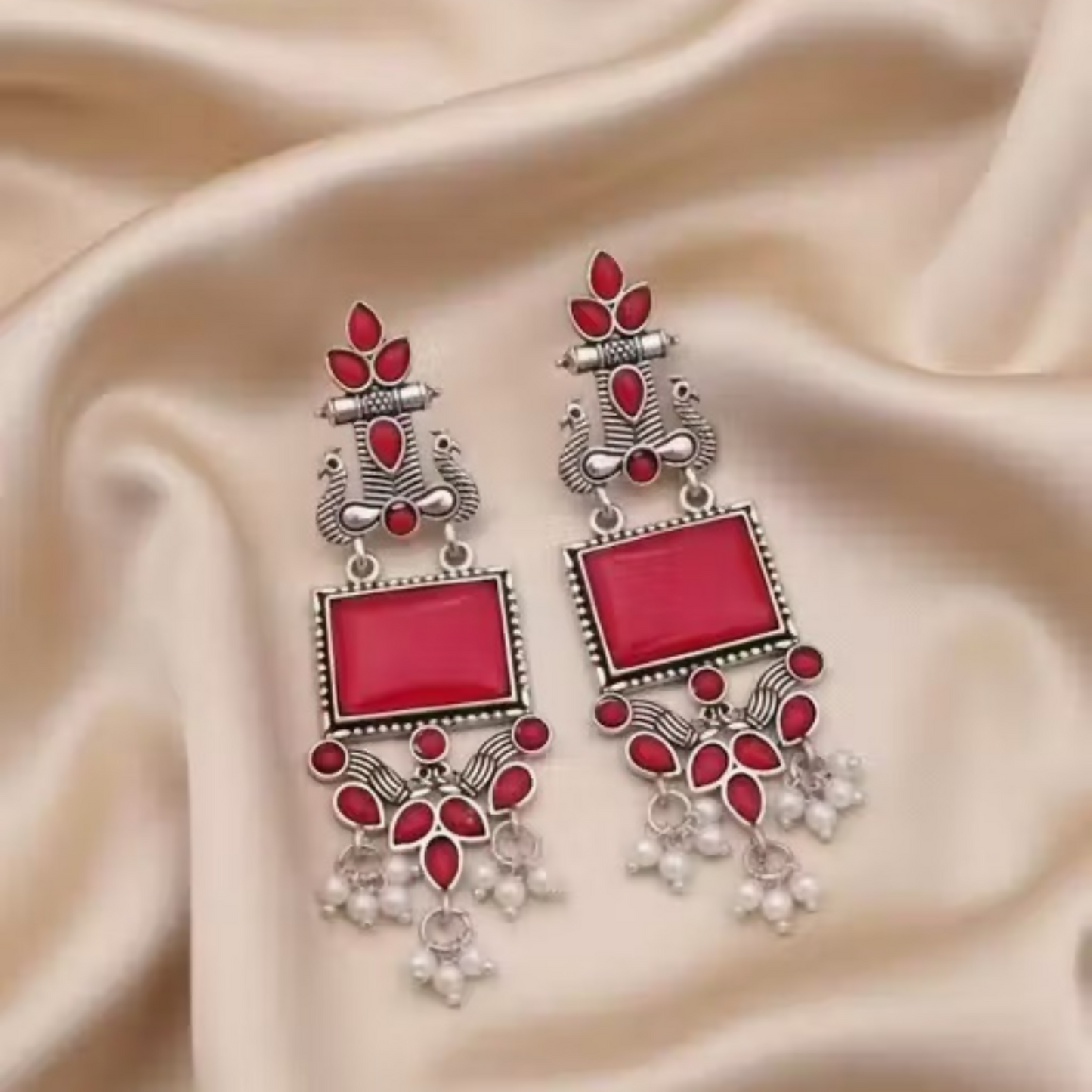 Oxidized silver earrings displayed on a white background highlighting red stones and pearls