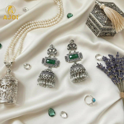 Imperial Heritage Oxidized Silver Jhumka Earrings with Deep Green Stone, Hand-Engraved Motifs, Crystal Accents & Pearl Drop Detailing.
