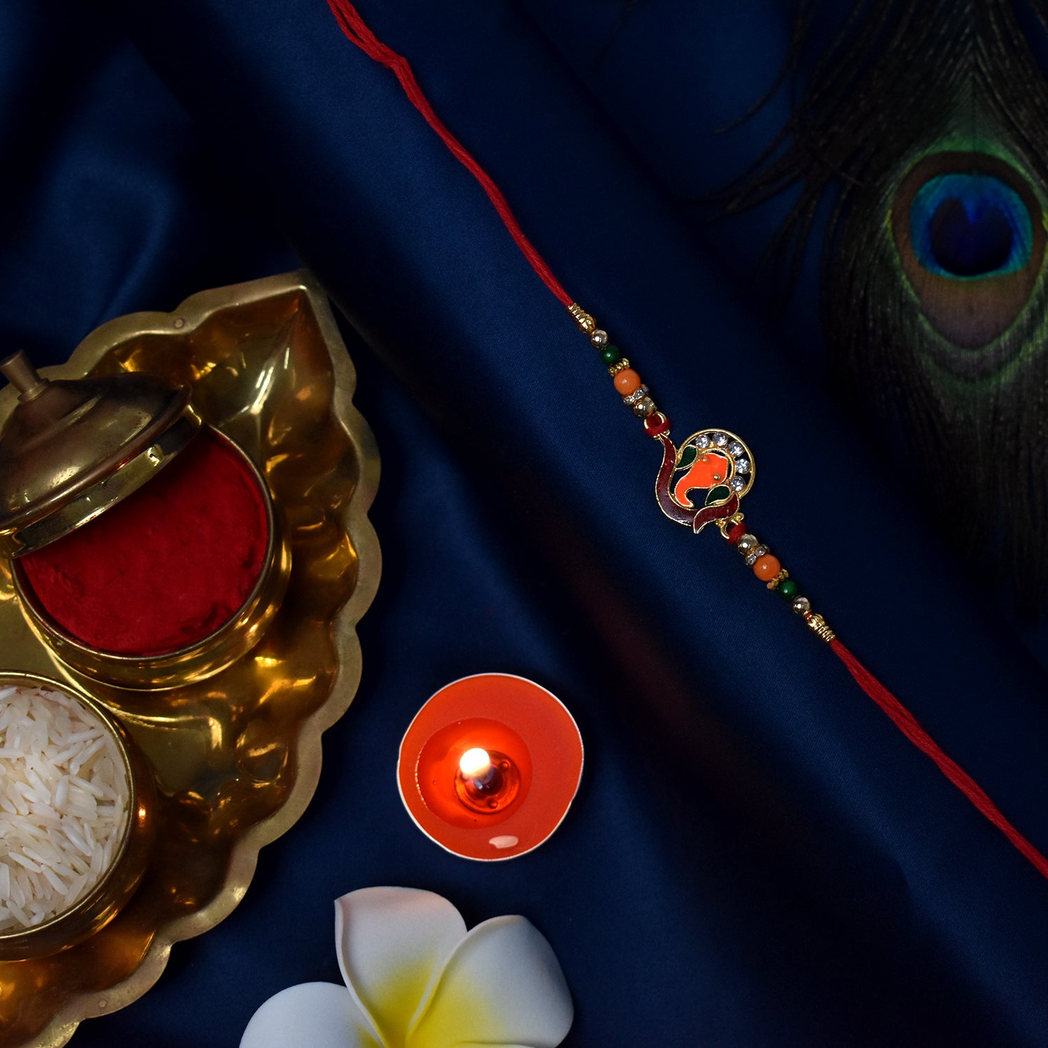 Golden Ganesha Rakhi with red and green beads and stone detailing