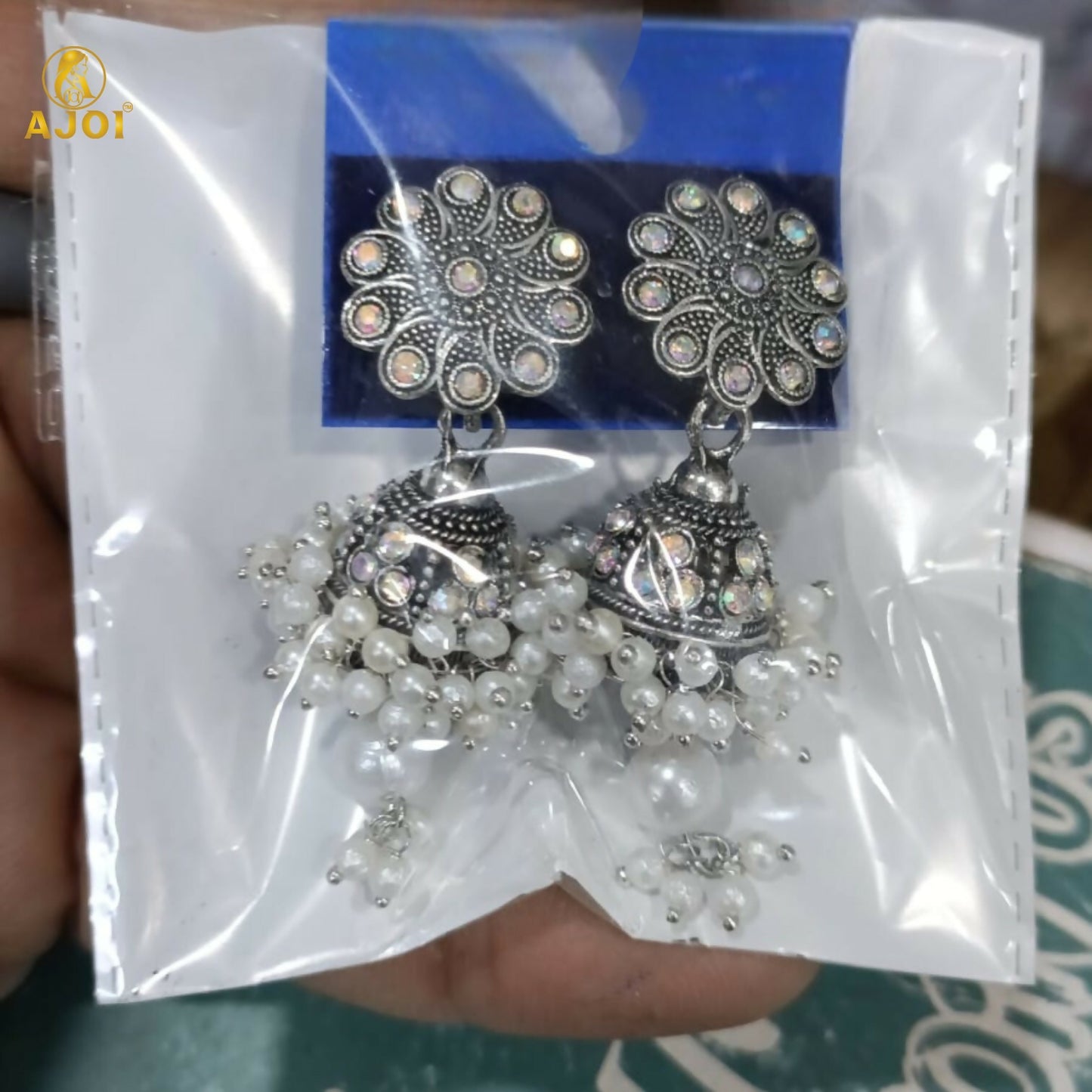 Pair of oxidised silver round jhumka earrings with pearls on white background
