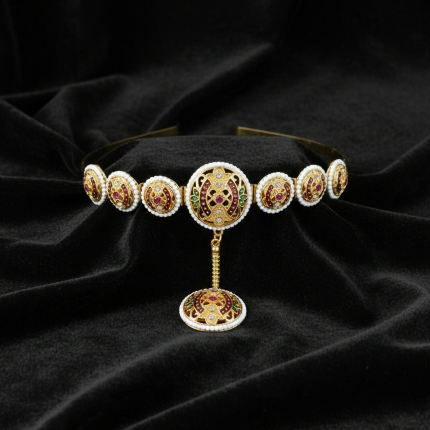 Close-up of vibrant ruby and emerald minakari stones and pearl border on Matha Patti