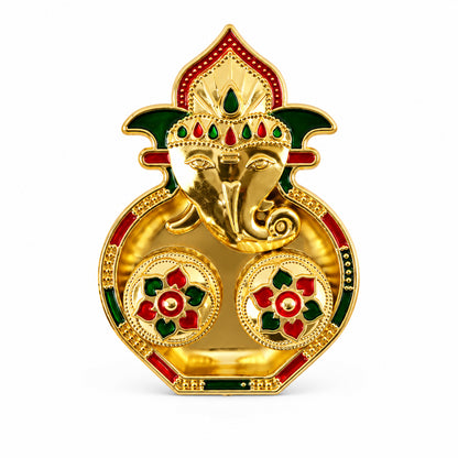A golden Ganesha-shaped kumkum holder with red and green enamel details on a white background.