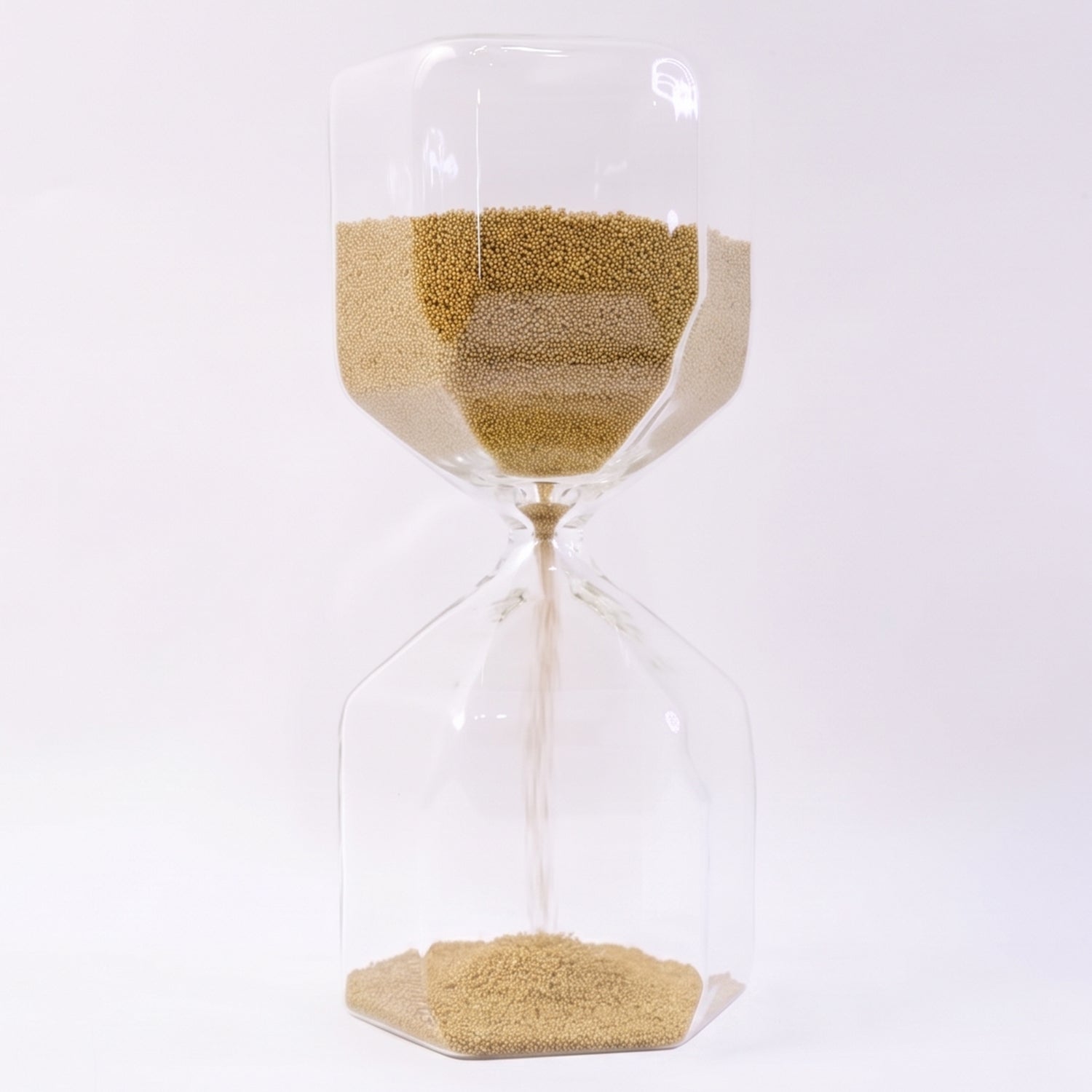 Close-up of fine yellow sand flowing in glass hourglass timer