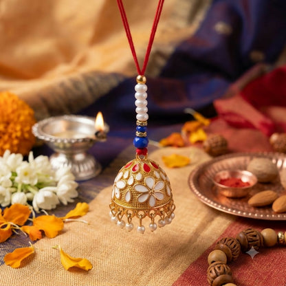 A gold-finished lumba with white and red enamel flowers and pearl drops hangs over a yellow and blue patterned fabric with