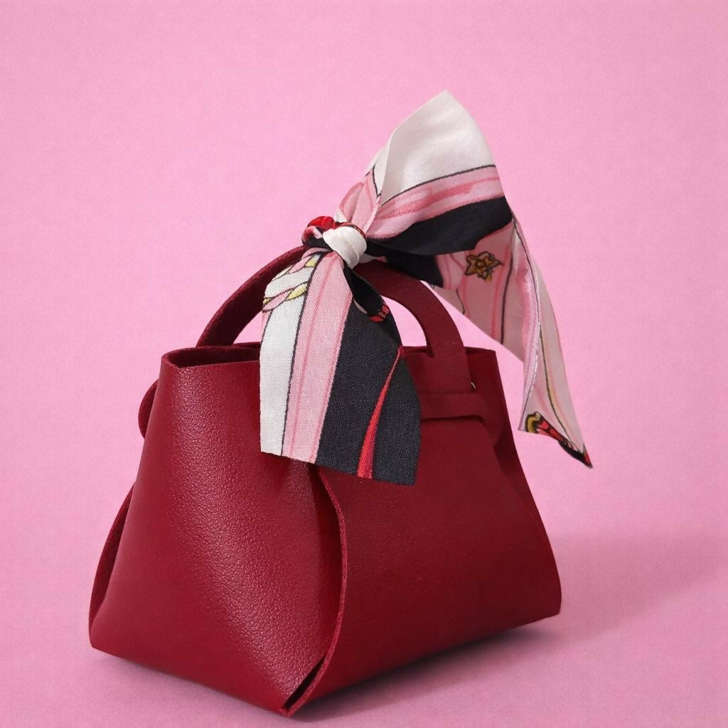 Close-up of printed ribbon bow on maroon mini handbag