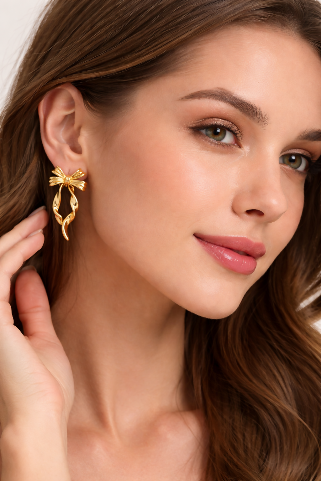 Gold bow drop earrings worn by model