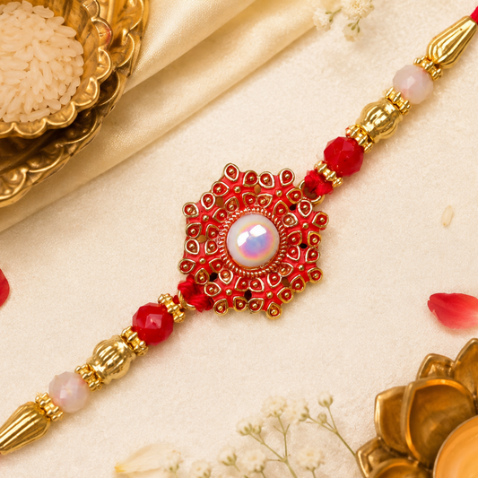 A red and gold beaded bracelet with a central red floral medallion featuring a white pearl, surrounded by traditional items.