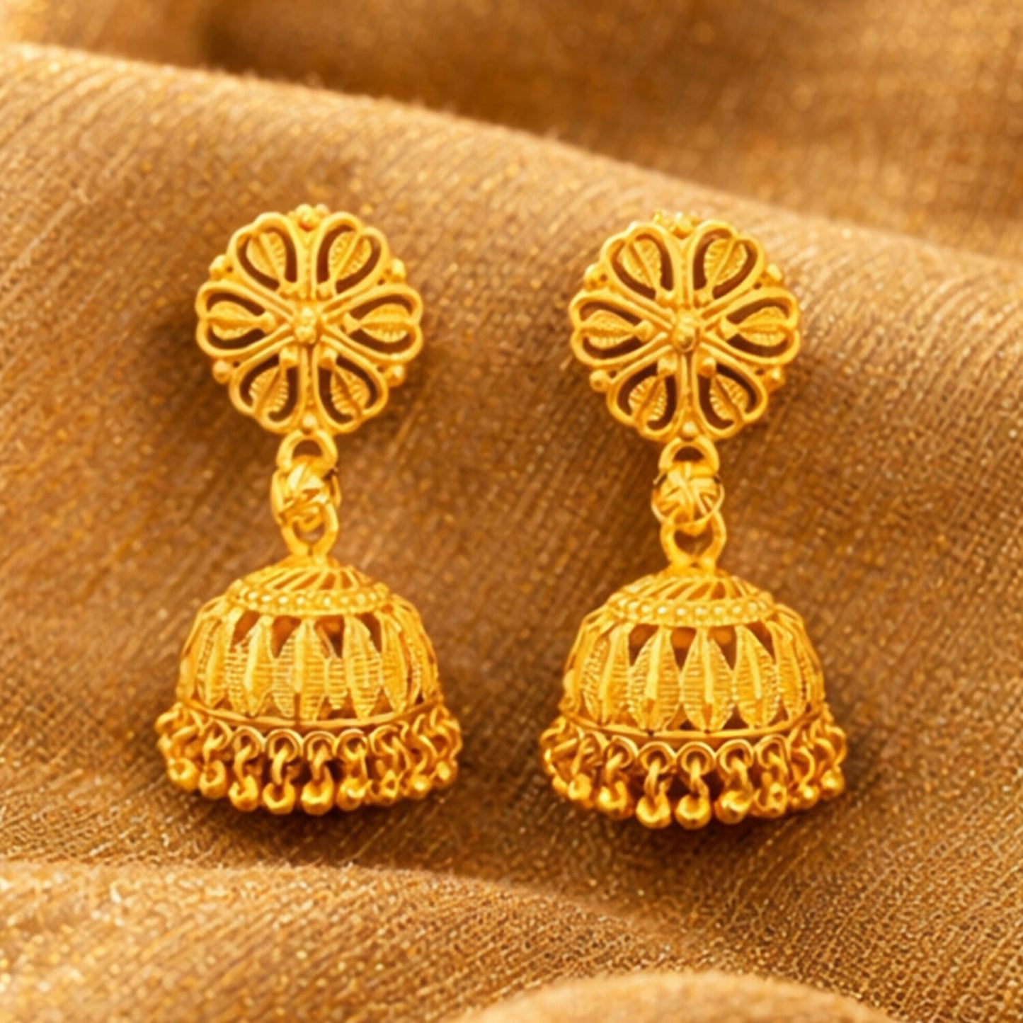Traditional gold plated jhumka earrings displayed on white background