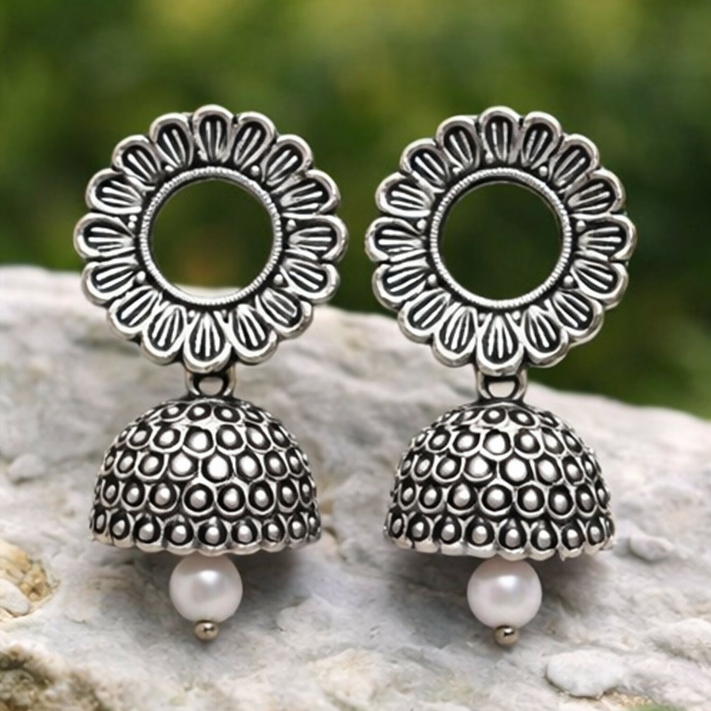 Close-up of traditional oxidized silver floral jhumka earrings highlighting craftsmanship