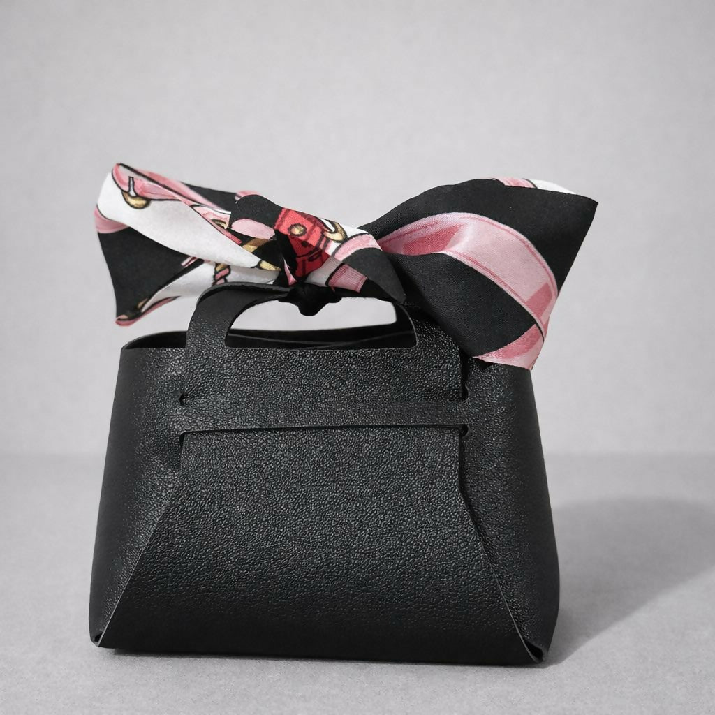 Woman holding a black mini coin pouch with bow