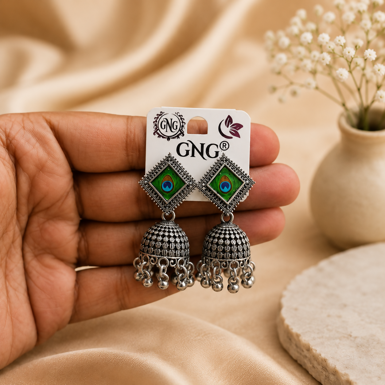 Close-up view of an oxidised jhumka earring showcasing the detailed peacock motif and dangling beads.