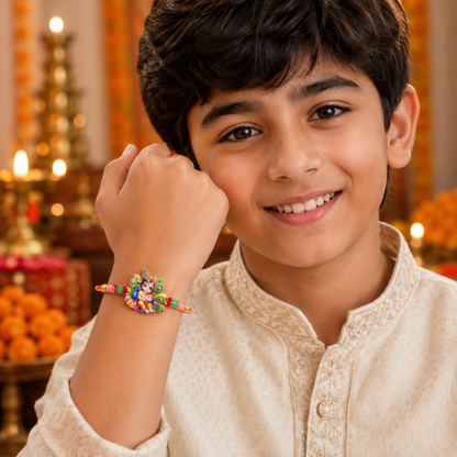 A young boy with dark hair and a light-colored kurta smiles, wearing a colorful Rakhi on his right wrist.