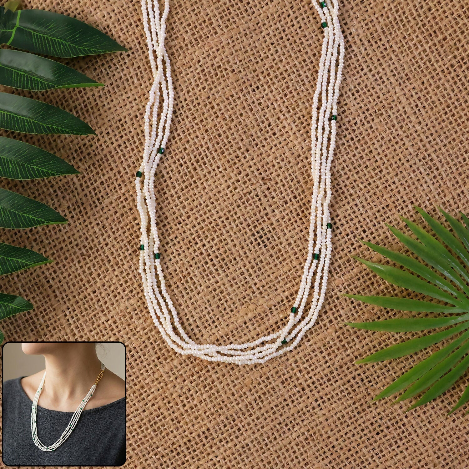 Multi-layer white beaded mala with green accents on a white background