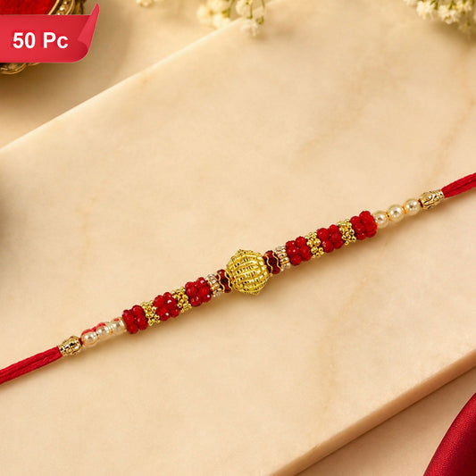 A red thread bracelet with a golden centerpiece, flanked by red beads and small white pearls, lies on a light marble surface.