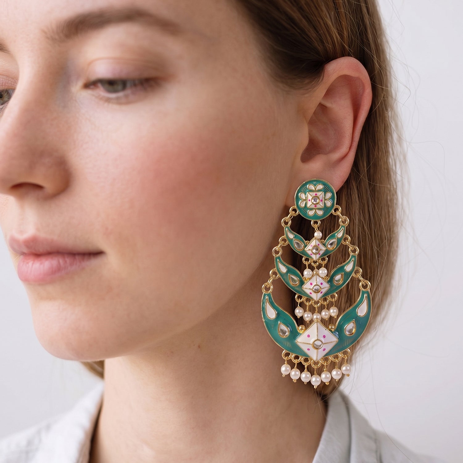 Detailed meenakari artwork on Emerald Pista earrings