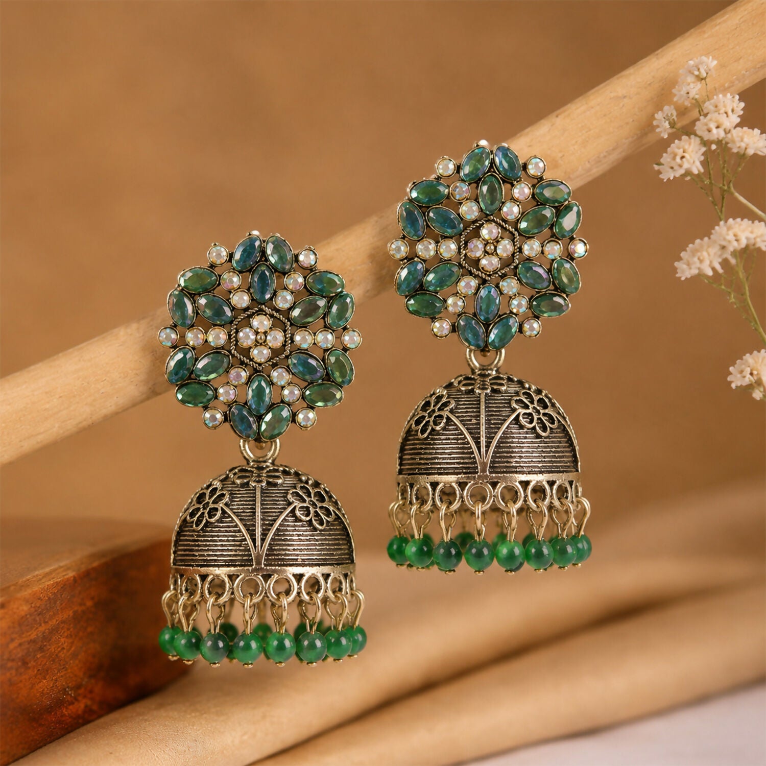 Close-up of carved dome design on antique golden green stone jhumka earrings