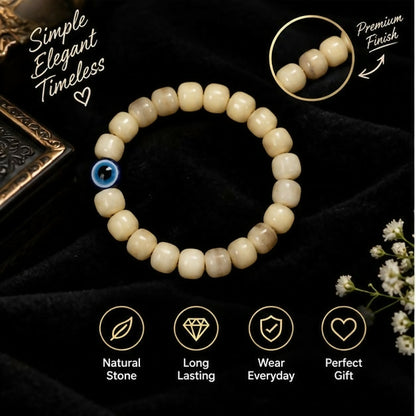 Cream barrel bead bracelet with blue evil eye accent on a wrist