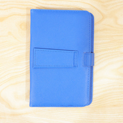 A closed blue PU leather tablet case with a flap closure is centered on a light wooden background.