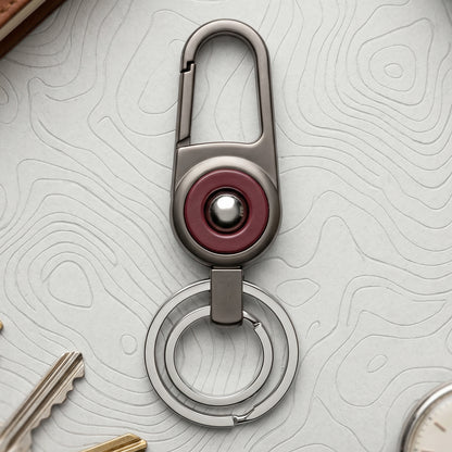 Durable metal key holder with dual rings and locking clip attached to a backpack