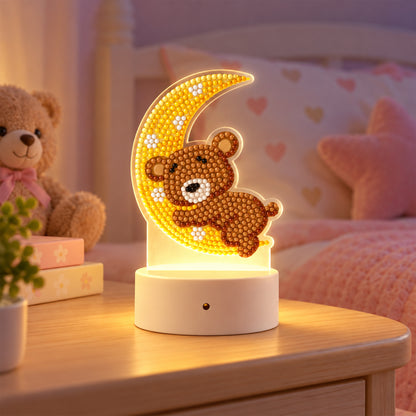 A diamond painting night light featuring a brown teddy bear on a yellow crescent moon, illuminating a child's bedroom.