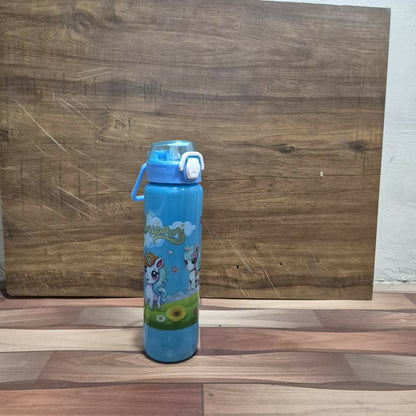 A light blue unicorn print water bottle with a straw and carry handle stands on a wooden floor against a wooden wall.