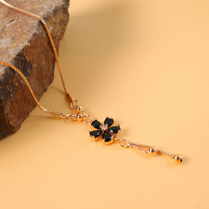 Hand model wearing gold finish black floral pendant necklace with elegant drop design