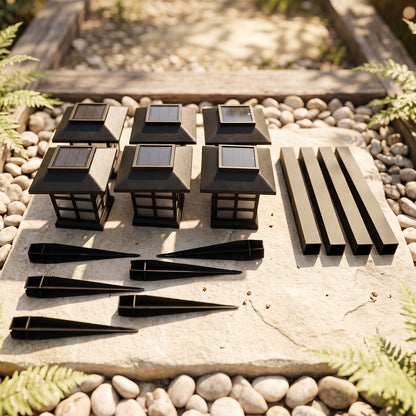 Six black solar lantern tops, six stakes, and six poles are laid out on a stone surface surrounded by pebbles.