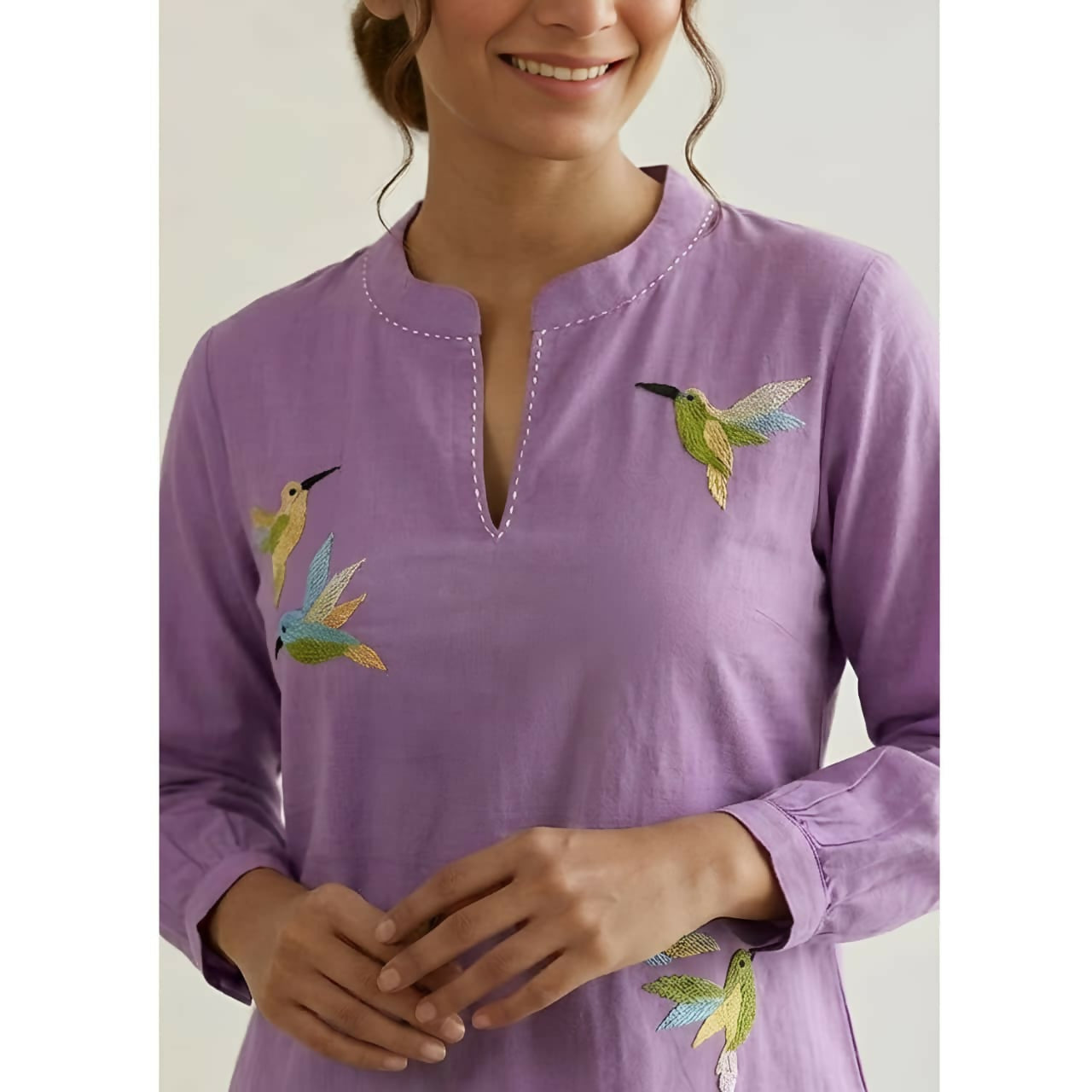 Close-up of delicate bird embroidery on purple cotton top
