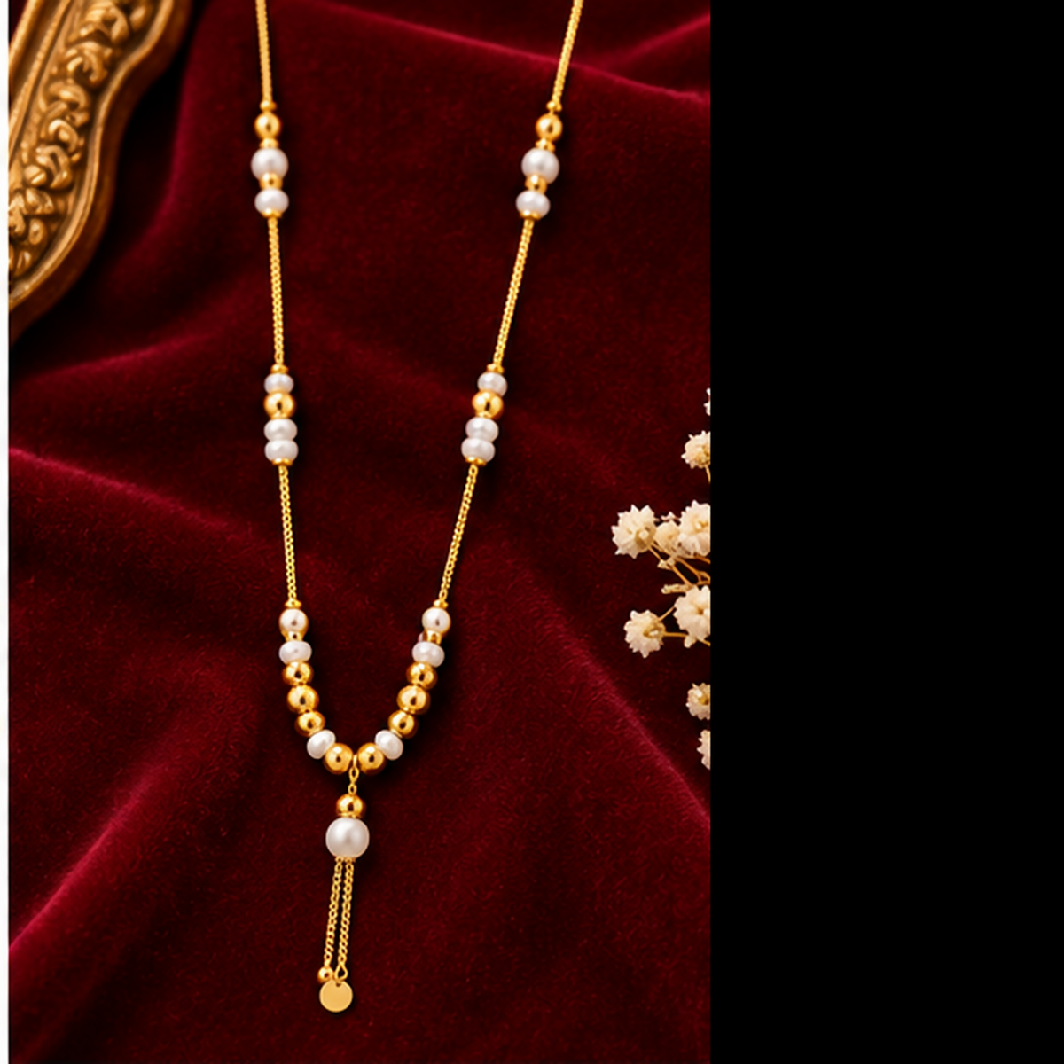 A gold tone necklace with white pearls and gold beads on a dark red velvet fabric with white flowers.