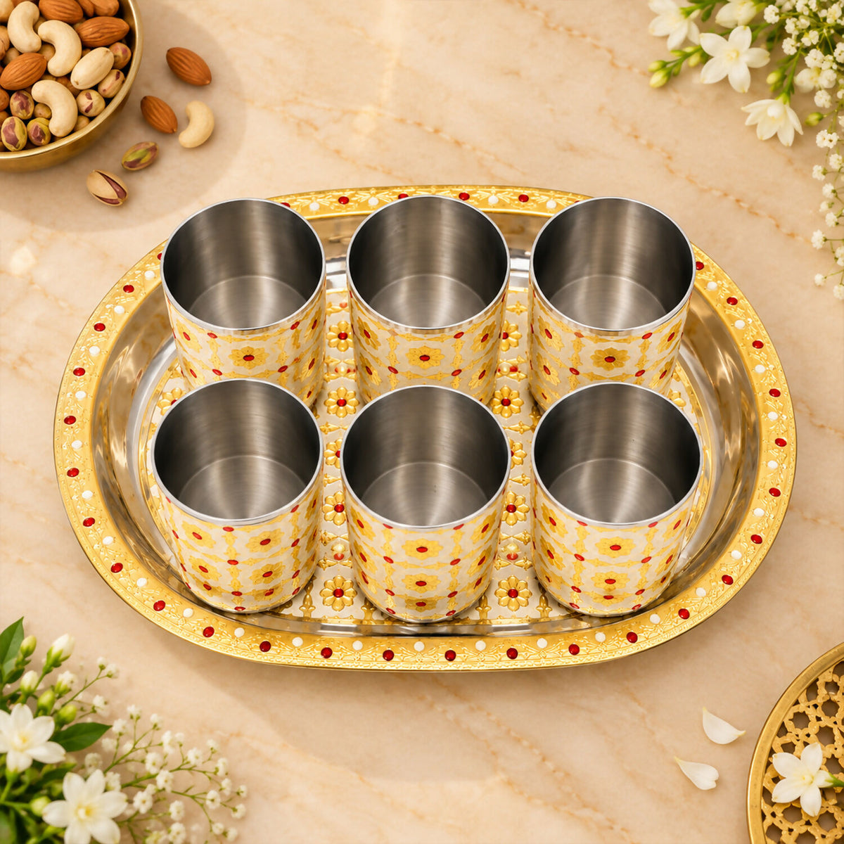 Six empty stainless steel glasses with a yellow and red floral pattern on a matching oval serving tray.