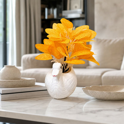 Decorative white ceramic swan vase with orange skeleton leaves on a table