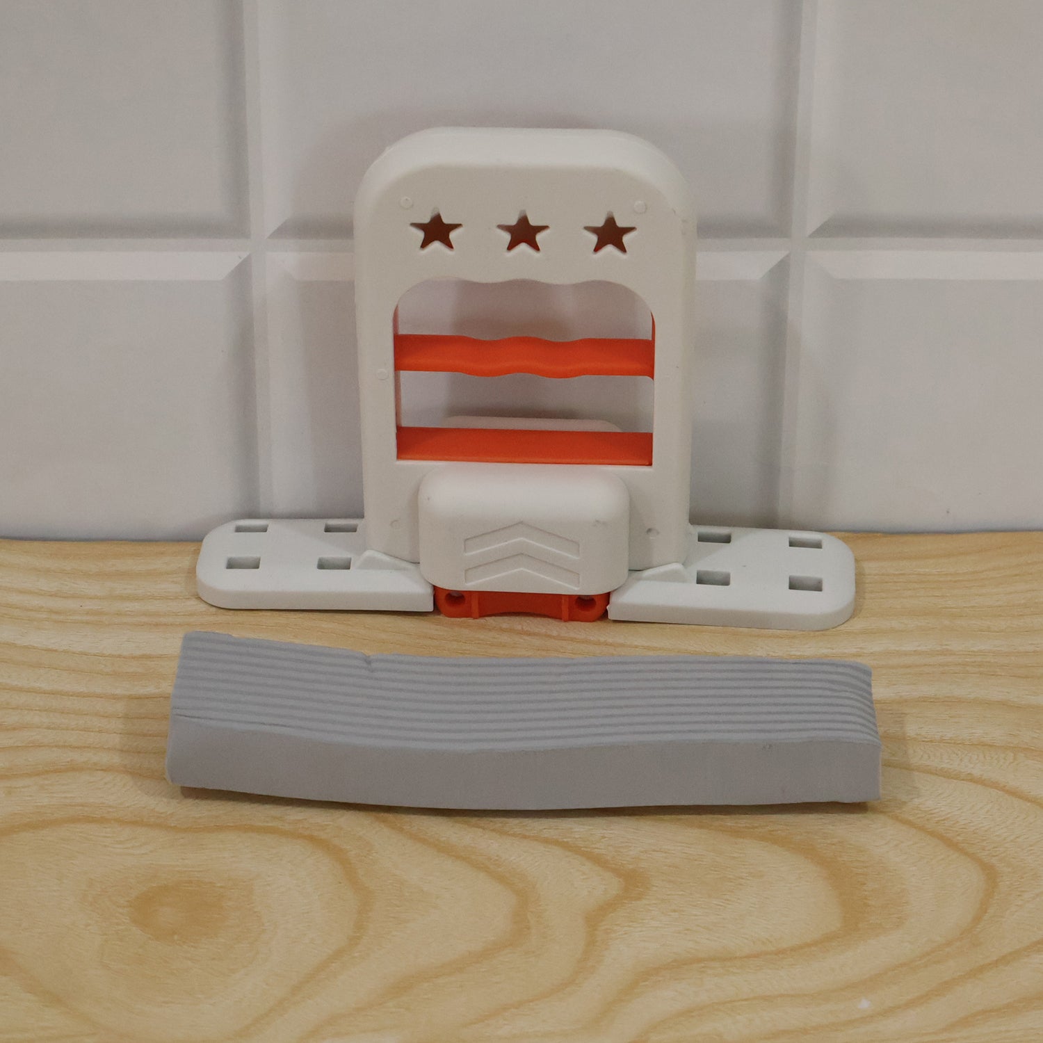 The white and orange mini mop is disassembled on a light wooden surface, with the gray sponge separate.