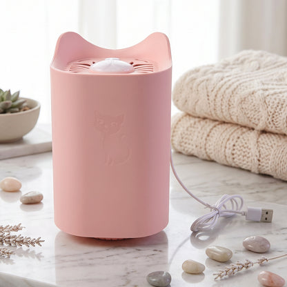 A pink cat-shaped mosquito killer lamp with an embossed cat design is on a marble surface with decorative stones and a