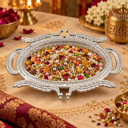 Silver-colored serving tray with mukhwas on a decorated table with golden accents and blurred background.