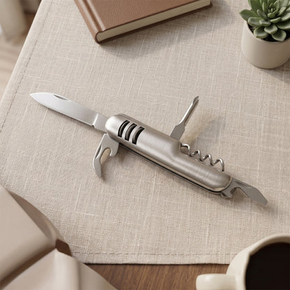 The silver multi-tool is shown with its screwdriver extended, next to a white box on a wooden surface.
