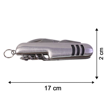 A hand uses the silver multi-tool's saw blade to cut a small branch from a tree.