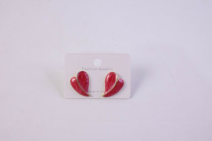 Lifestyle image of woman wearing red leaf stud earrings with gold outline