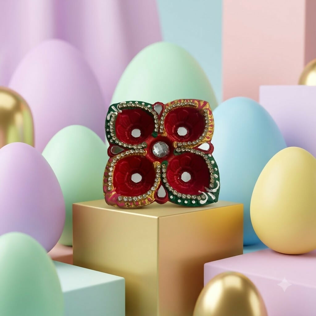 A decorative four-cup diya with red, green, and gold colors, mirrors, and gems rests on a gold pedestal amidst pastel eggs.
